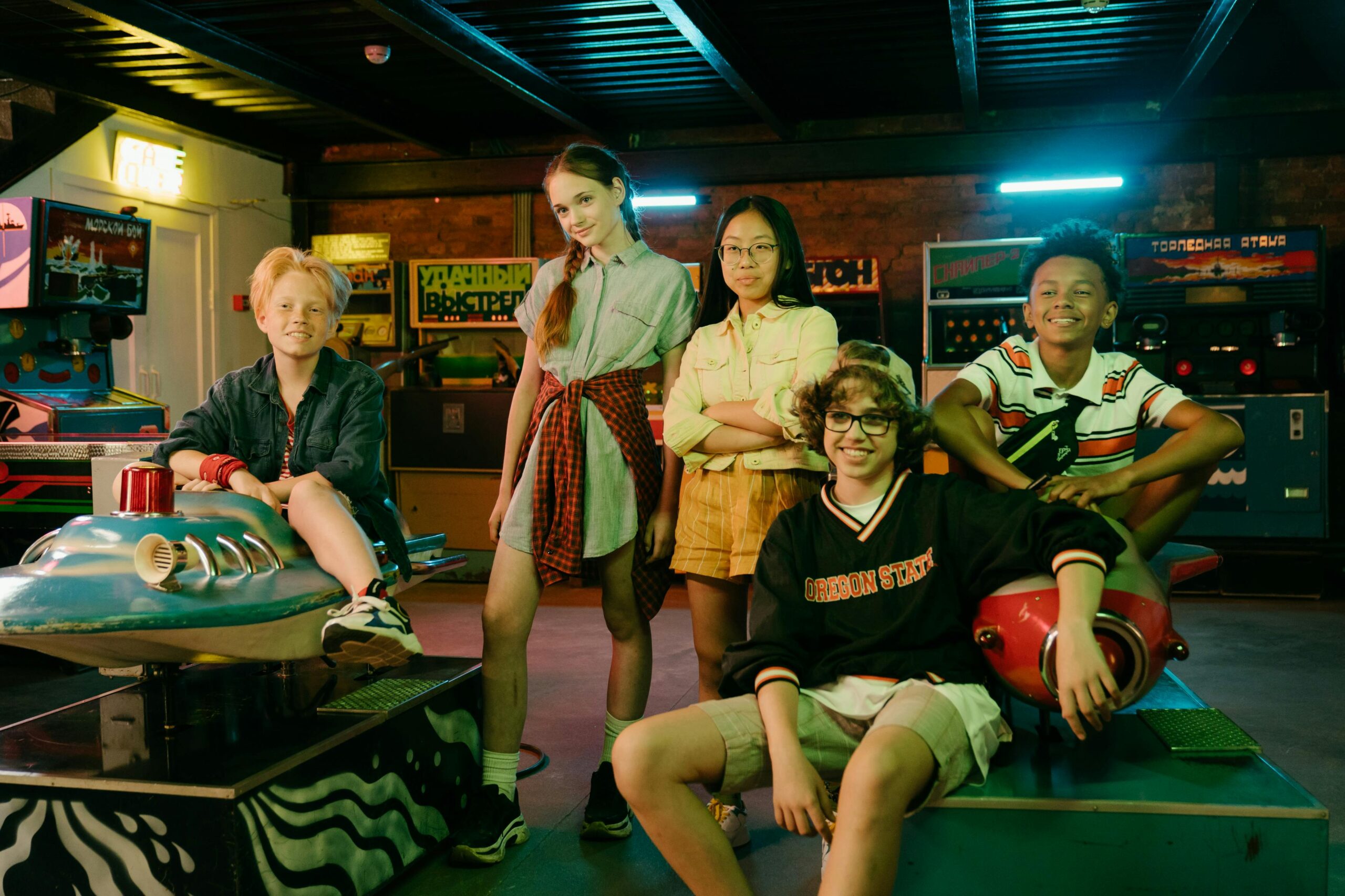 Diverse group of teens having fun in a vintage arcade with retro games and vibrant neon lights.